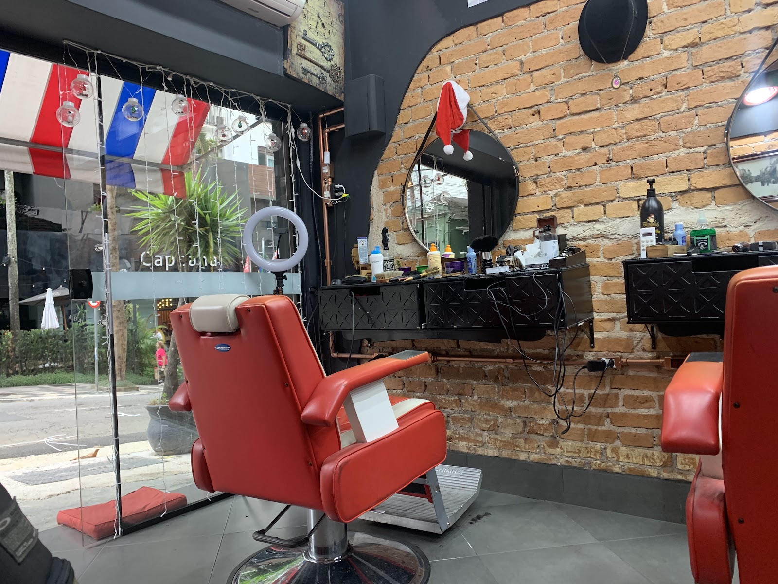 Salão com parede de tijolo aparente e cadeira vermelha de barbeiro